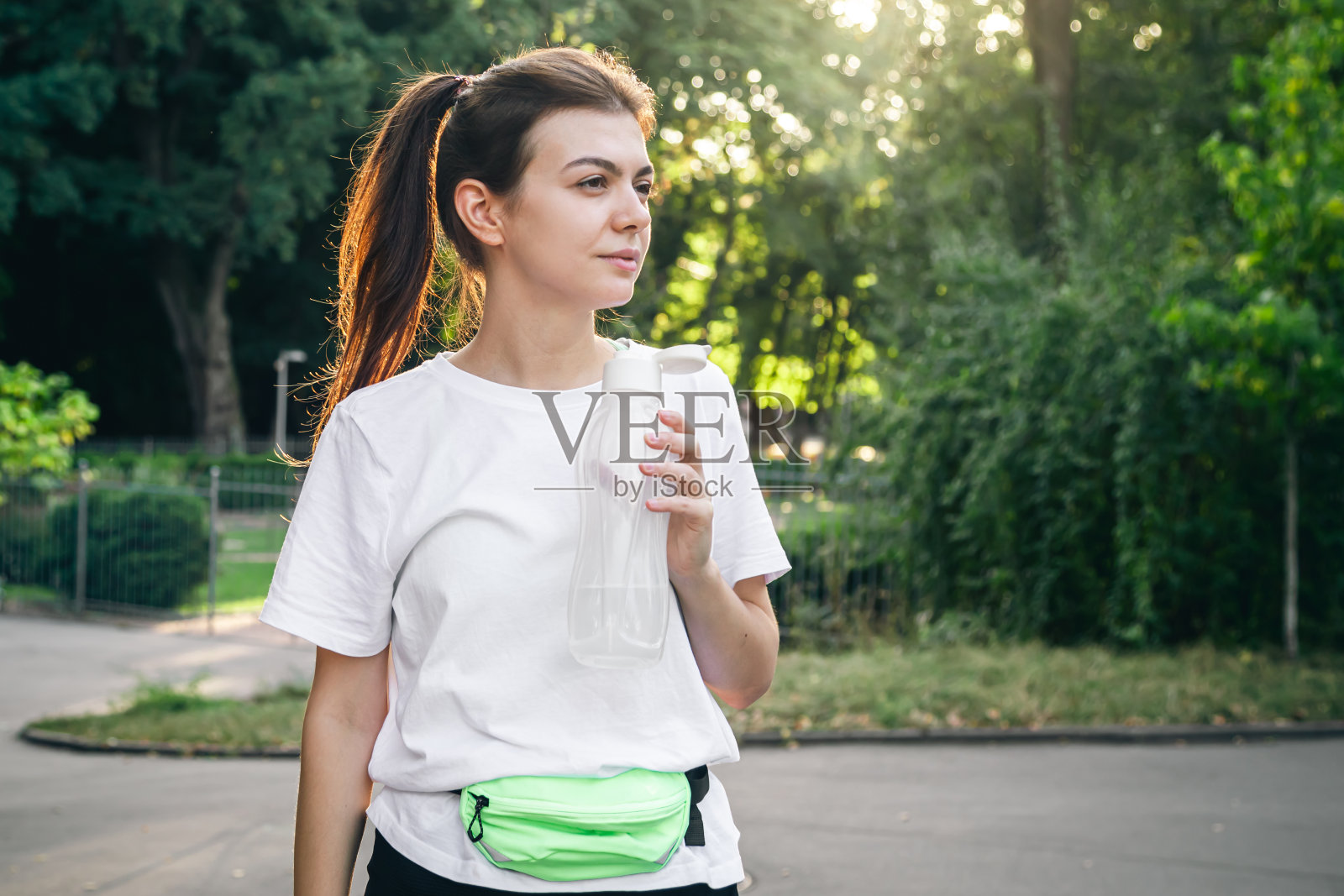 有魅力的年轻女子在户外运动后喝水。照片摄影图片