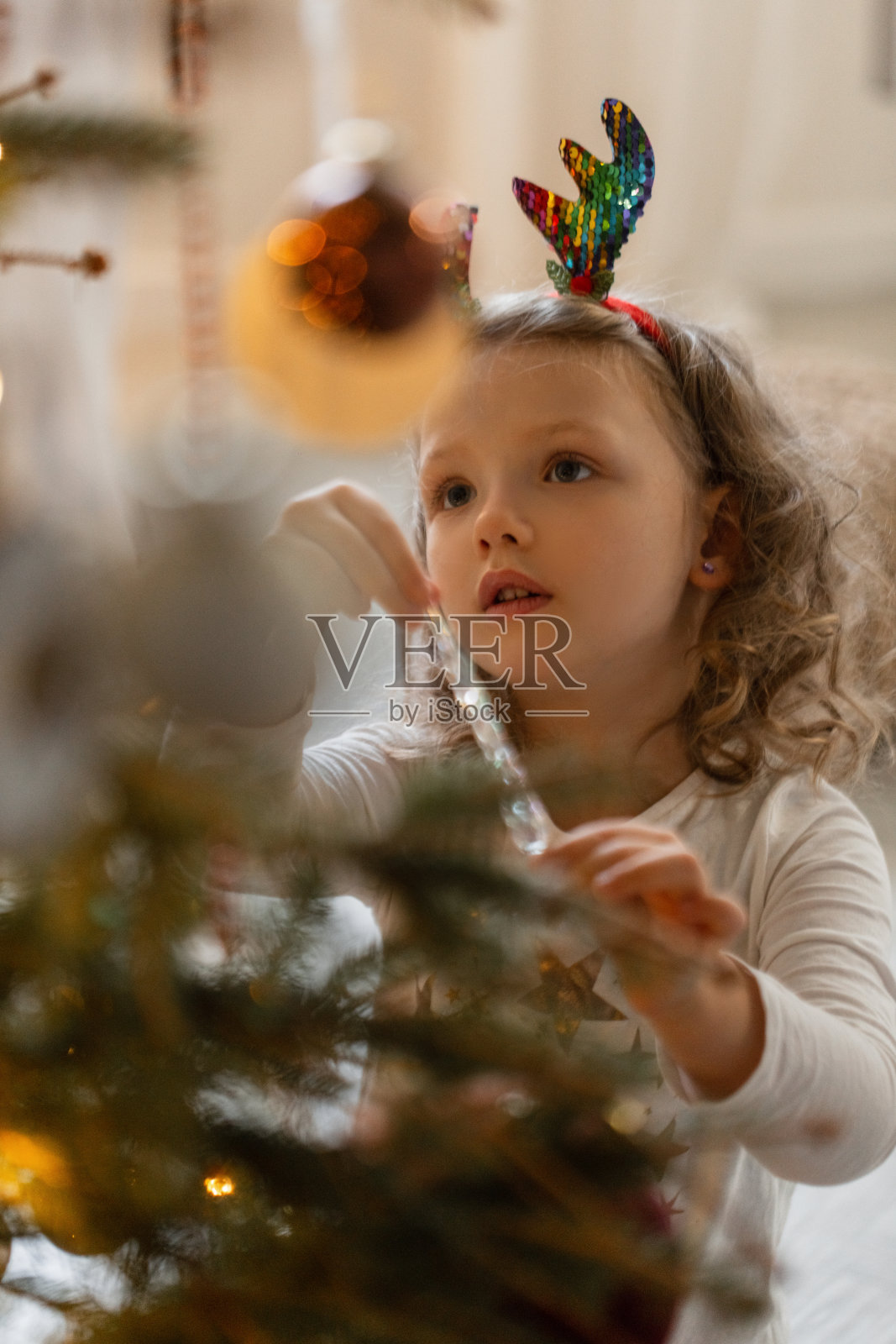 美丽的小女孩在平安夜装饰圣诞树，等待奇迹的出现照片摄影图片