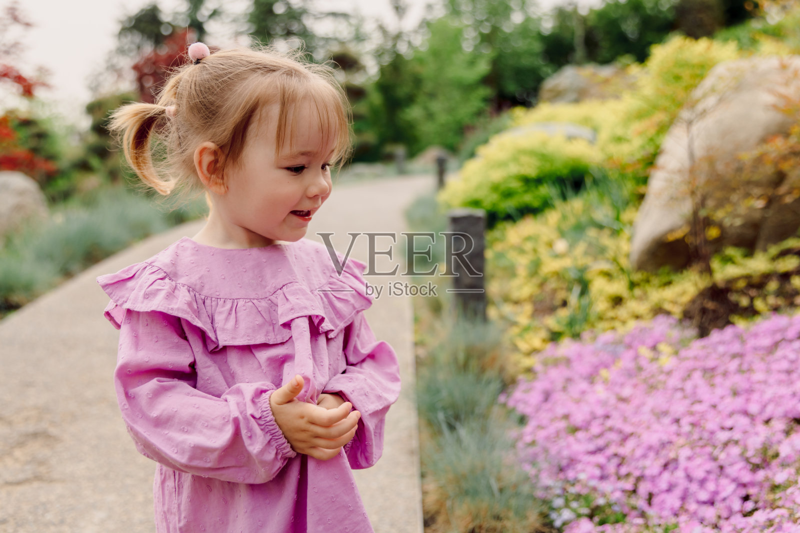 在盛开的花园或公园里微笑的小女孩的肖像。照片摄影图片