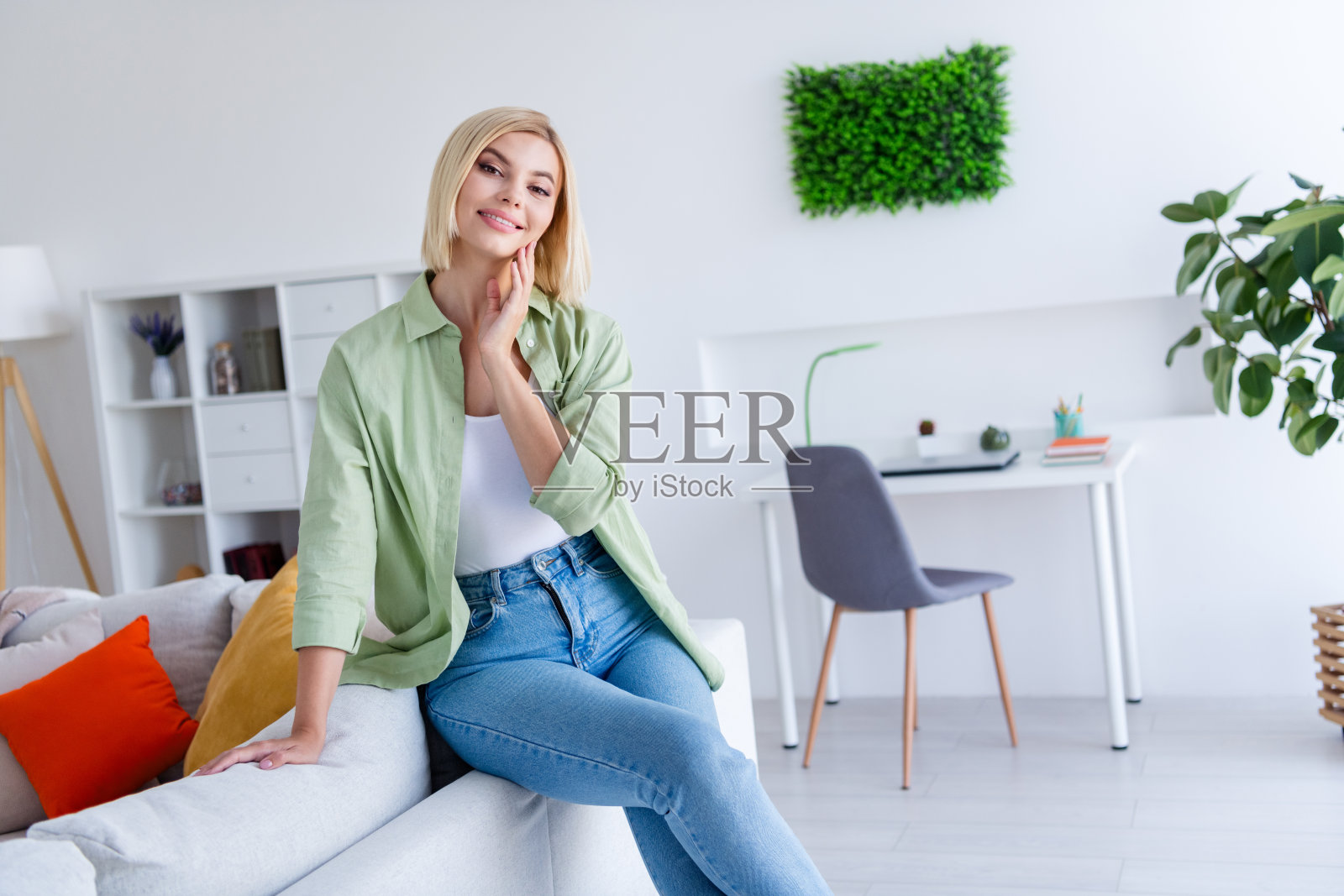 可爱可爱的漂亮女士坐在沙发上，在她舒适的工作空间白色现代室内的照片照片摄影图片