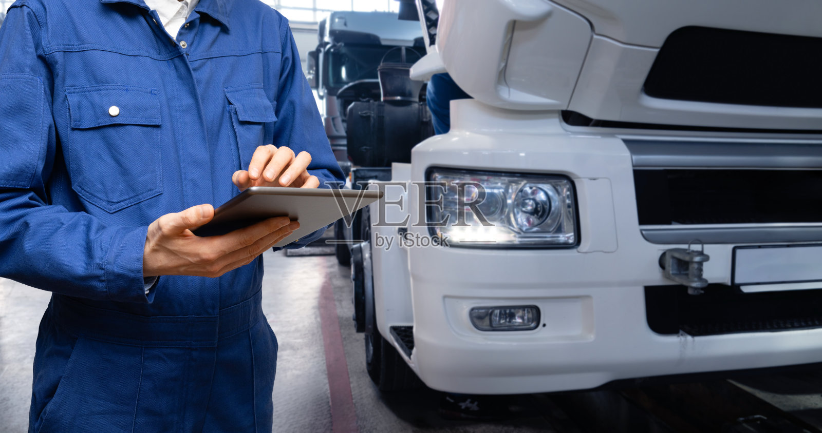 维修人员在车库卡车背景下手持平板电脑照片摄影图片