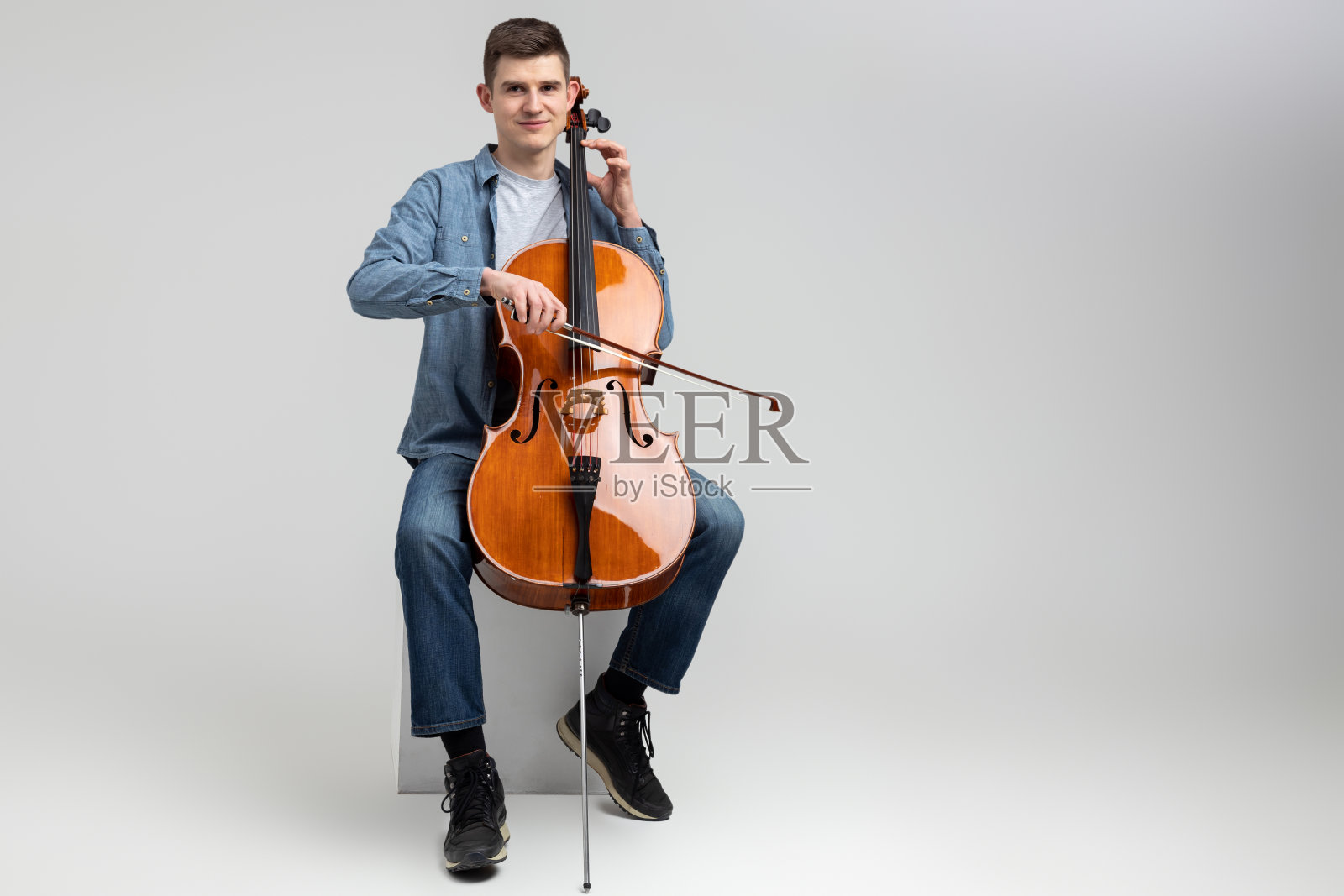 在音乐会上演奏大提琴的帅哥音乐家照片摄影图片