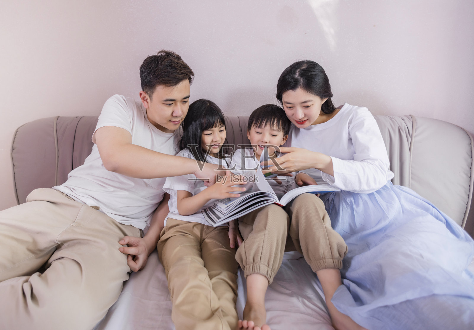 一个四口之家在卧室的床上照片摄影图片