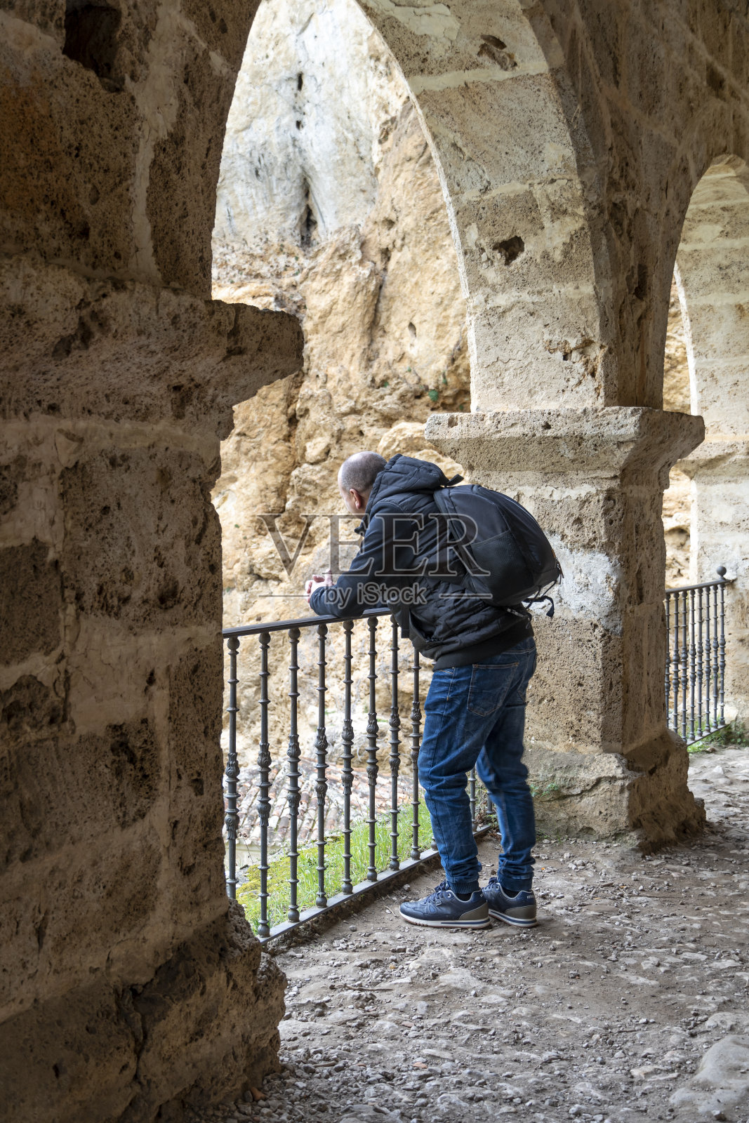 一名游客在石拱之间观察农村地区的周围环境。照片摄影图片