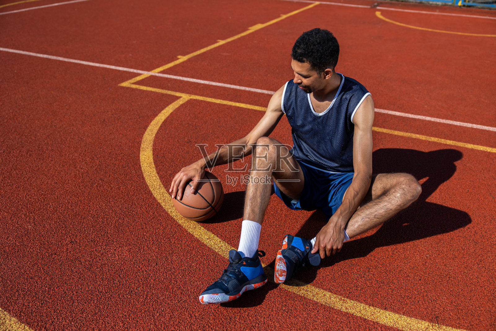 英俊的篮球运动员坐在室外球场上照片摄影图片