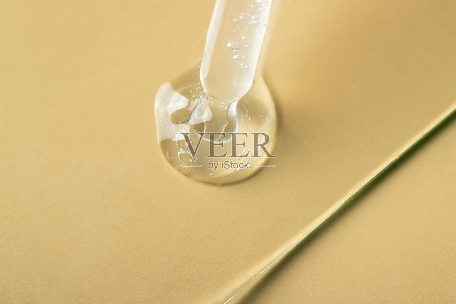 顶部视图移液管与闪亮的透明液体在米色背景与阴影。照片摄影图片