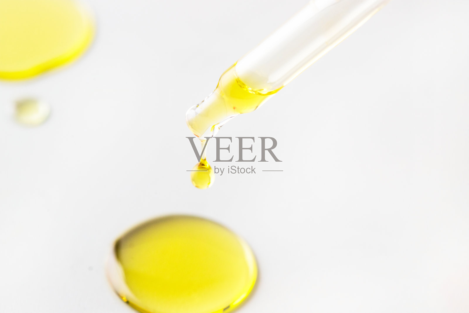 滴管移液器滴下面部油或精华液，黄色涂抹滴在白色背景上。近距离照片摄影图片