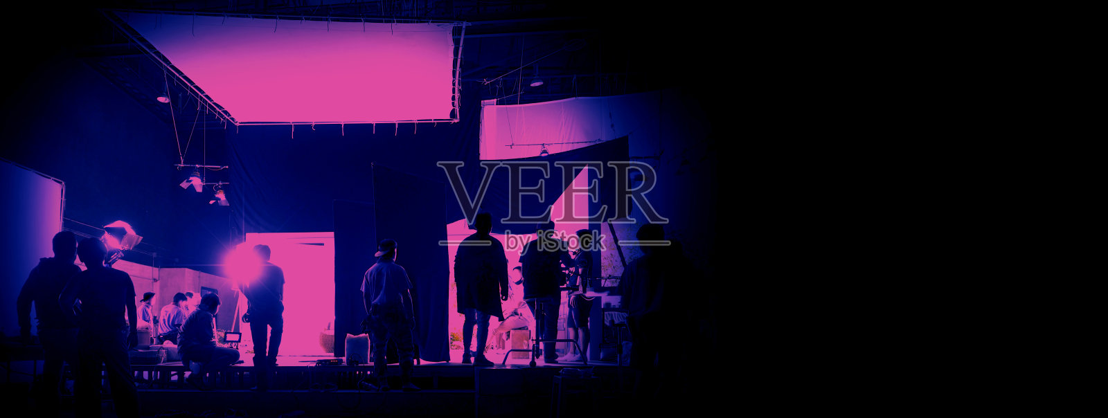 在大型制作工作室工作的人的剪影，用数码相机和灯光设备拍摄或录制电影视频。照片摄影图片