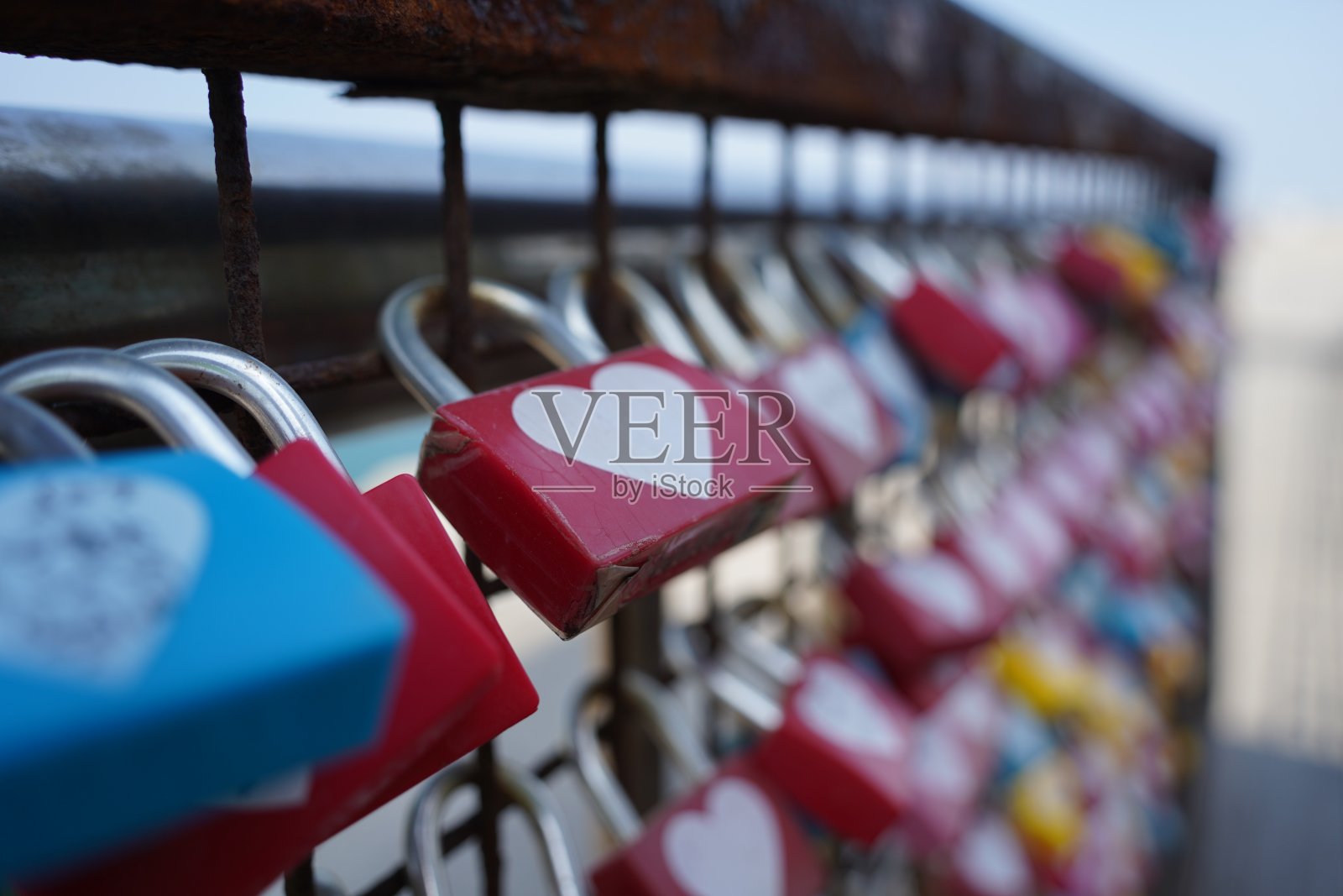 栅栏上五颜六色的心形挂锁。照片摄影图片