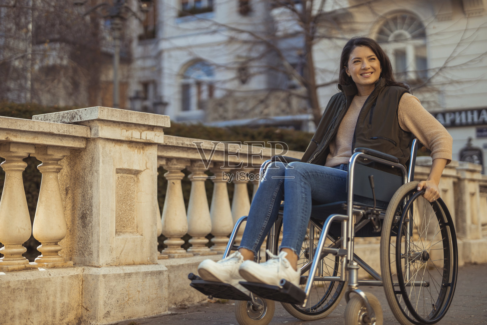 微笑的年轻残疾妇女坐在轮椅上的城市街照片摄影图片