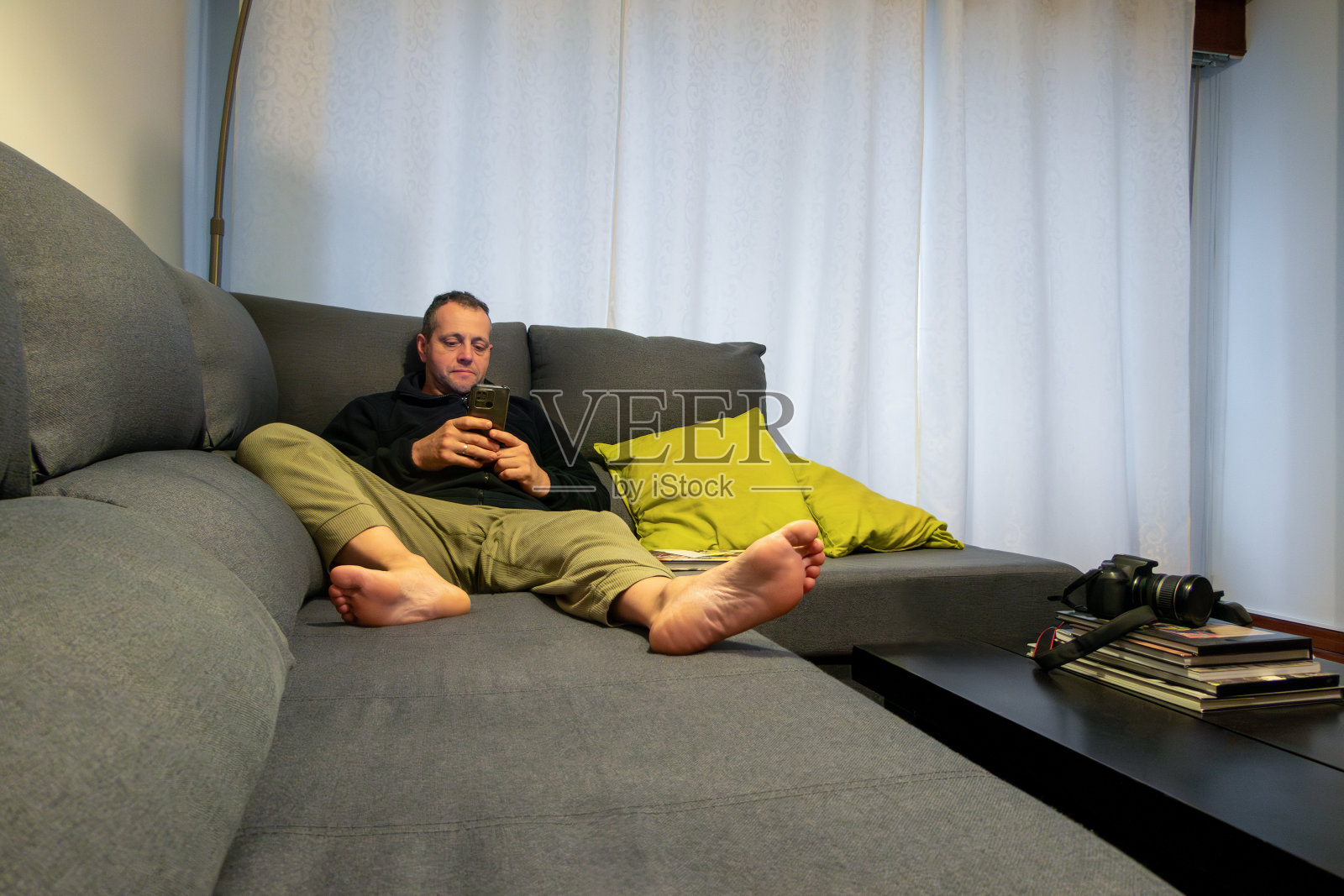 一个男人坐在大沙发上看他的智能手机照片摄影图片