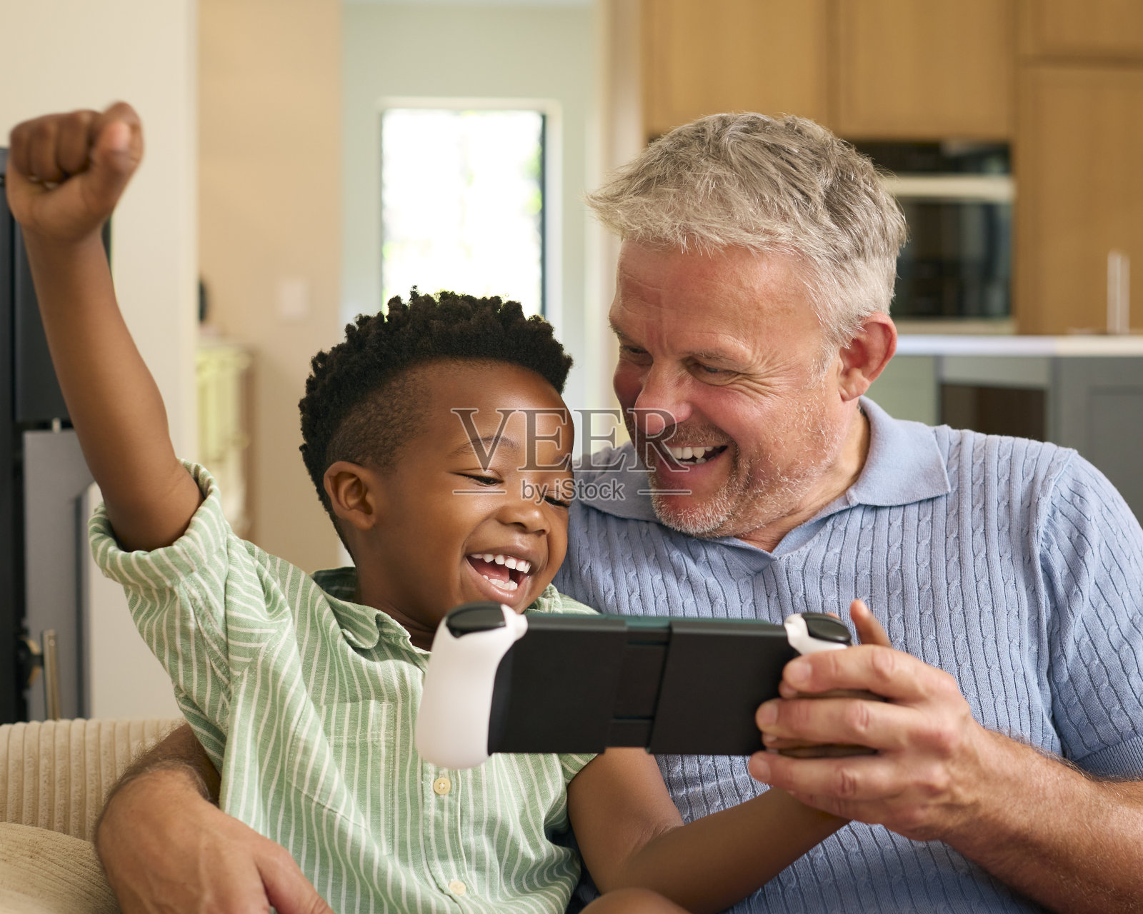 多种族家庭，爷爷和孙子一起玩掌上游戏机照片摄影图片