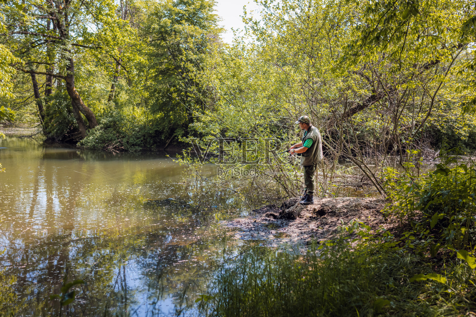 渔夫在河边钓鱼，周围是美丽的大自然照片摄影图片