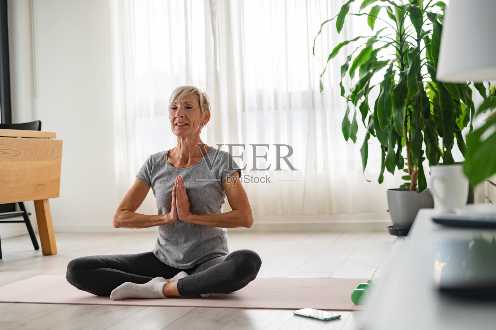 活跃的老妇人在室内练习瑜伽照片摄影图片