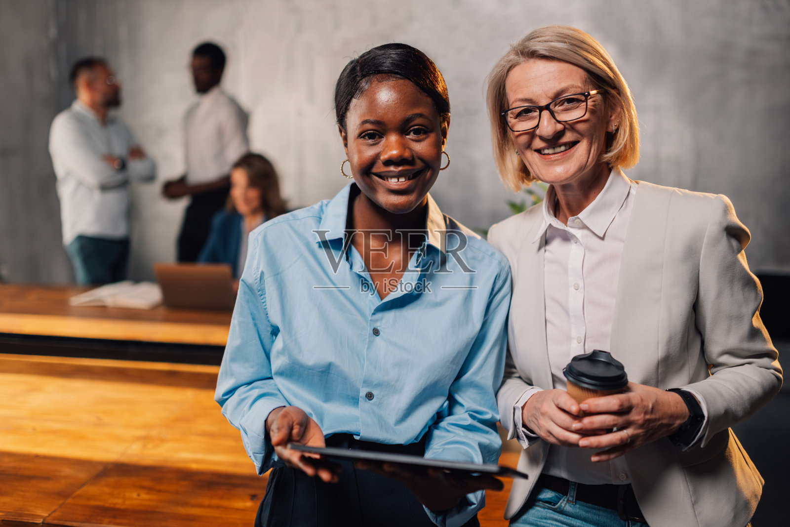 微笑的跨种族女商人在办公室拿着平板电脑看着镜头照片摄影图片