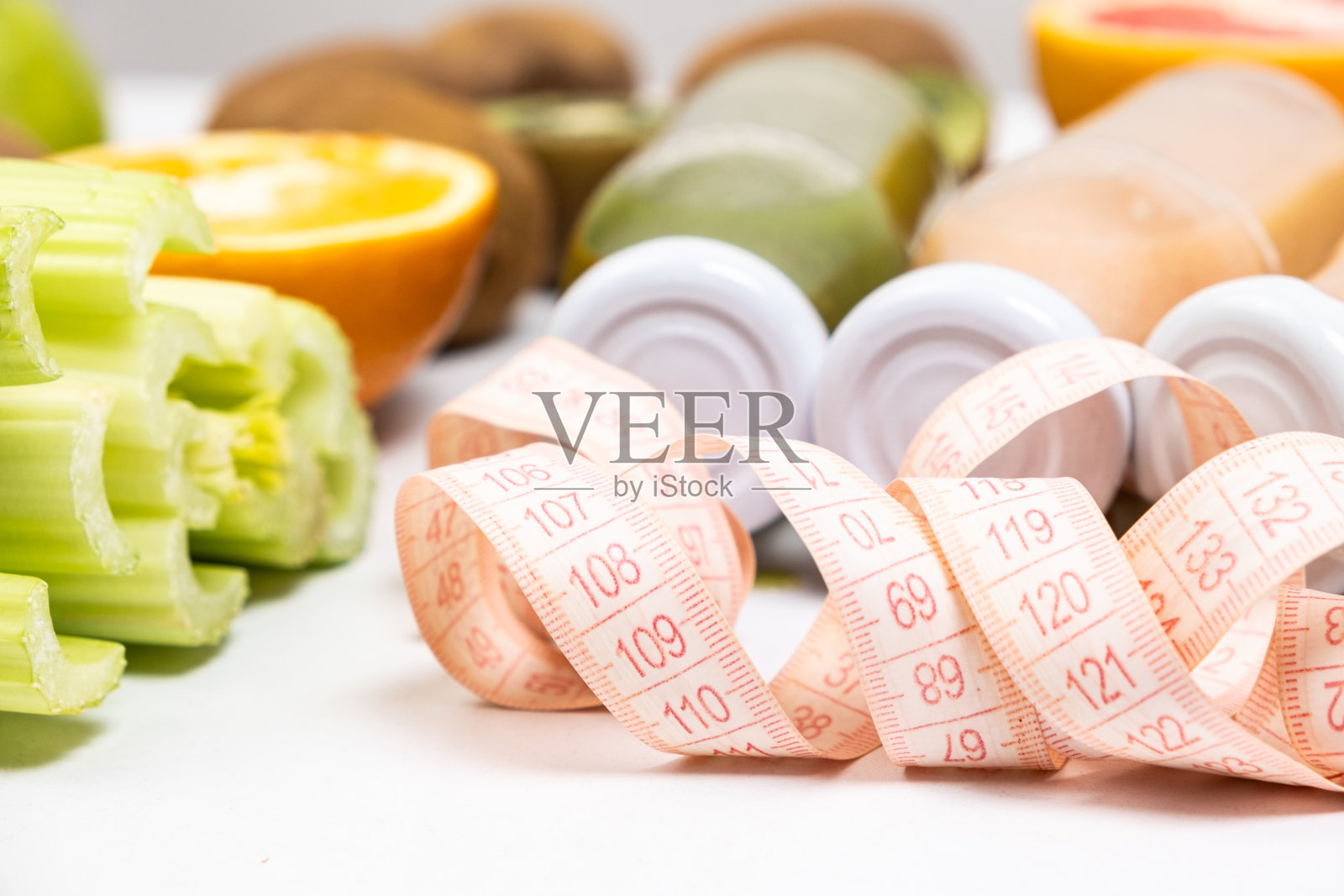 卷尺和瓶装冰沙在蔬菜和水果之间。适当的营养和减肥理念。照片摄影图片