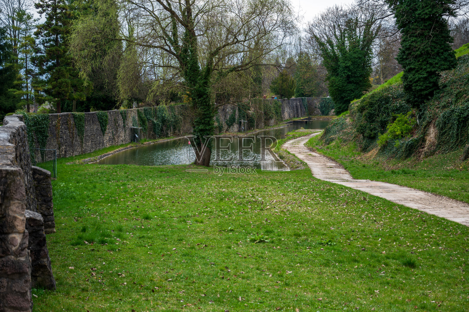 有护城河的历史性石墙。绿色的草坪和树木。照片摄影图片