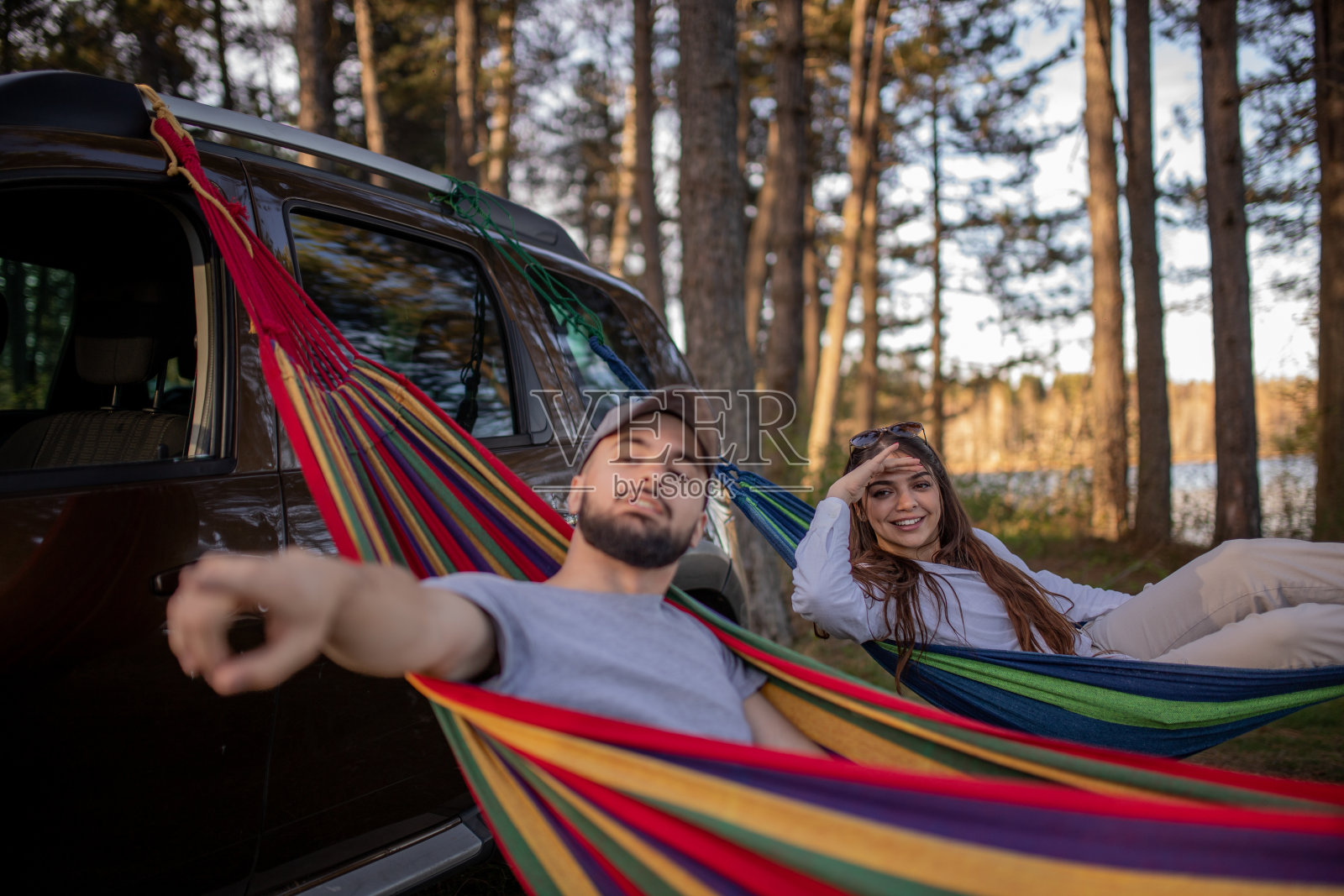 年轻夫妇在吊床上休息，露营时，男人指着什么照片摄影图片