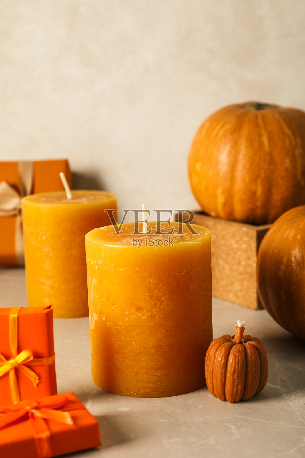 米色背景上的蜡烛、南瓜和礼品盒照片摄影图片