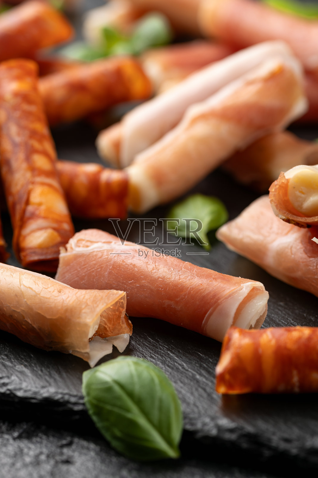 派对食品板的选择。塞拉诺火腿，意大利熏火腿和西班牙香肠卷填充豪达干酪和伊比利亚奶酪。照片摄影图片