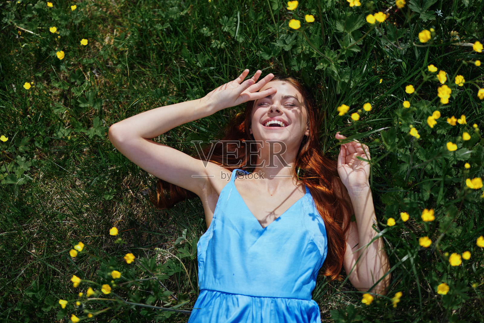 一个春天的女人，躺在绿草上，开着黄花，笑着，笑着，幸福地穿着蓝衣服，没有过敏的生活方式照片摄影图片
