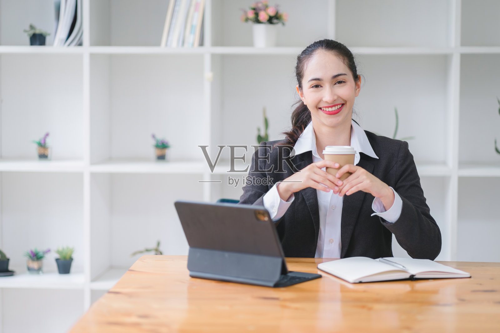 快乐的女商人一边在咖啡馆工作一边喝咖啡。照片摄影图片