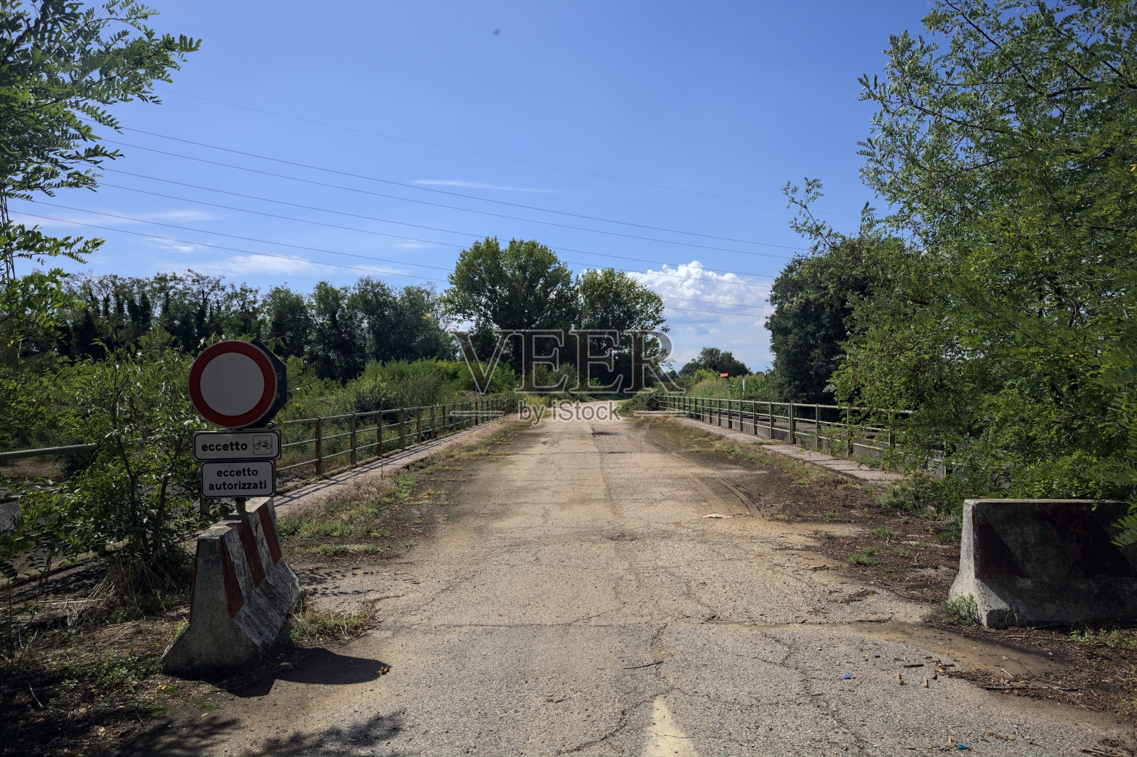 在一个阳光明媚的日子里，意大利乡村，混凝土屏障挡住了破旧的沥青桥照片摄影图片