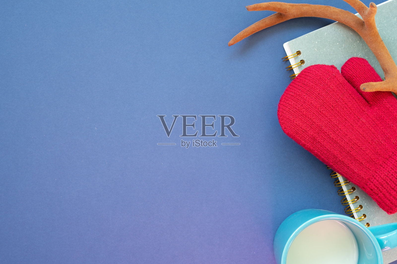 冬季针织红手套，鹿角，笔记本，一杯牛奶在深蓝色的背景。俯视图，复制空间照片摄影图片