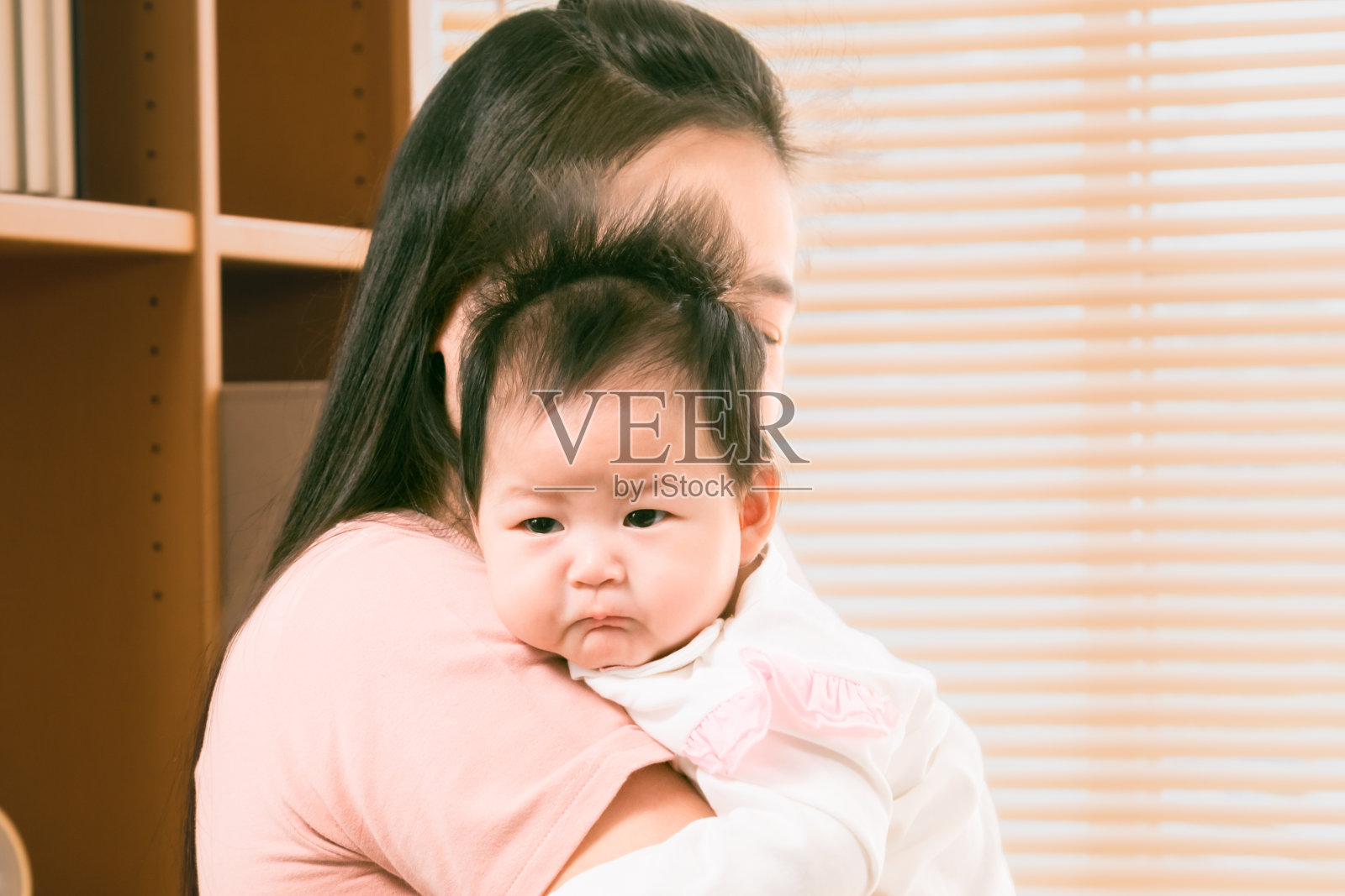 母亲怀抱新生婴儿的背影，充满爱和关怀。可爱的婴儿带着纯真环顾四周，快乐的妇女在分娩后在家照顾婴儿。照片摄影图片