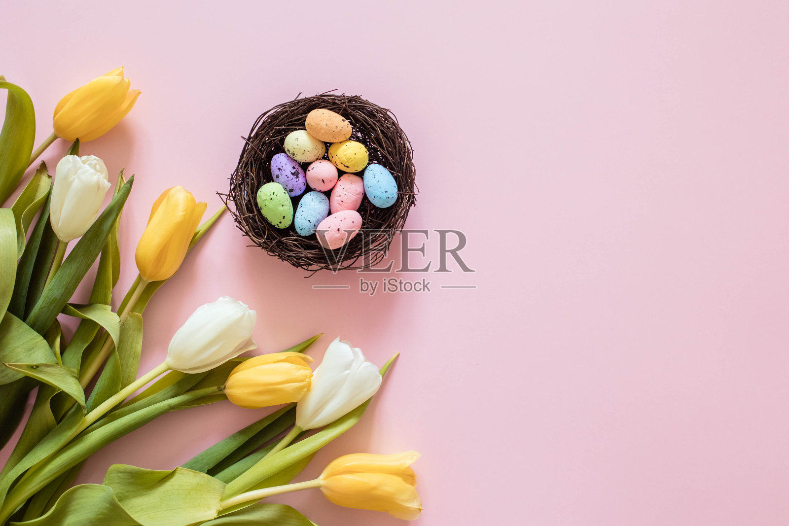 复活节卡片上有蛋在巢和郁金香，在粉红色的背景上，复制空间照片摄影图片