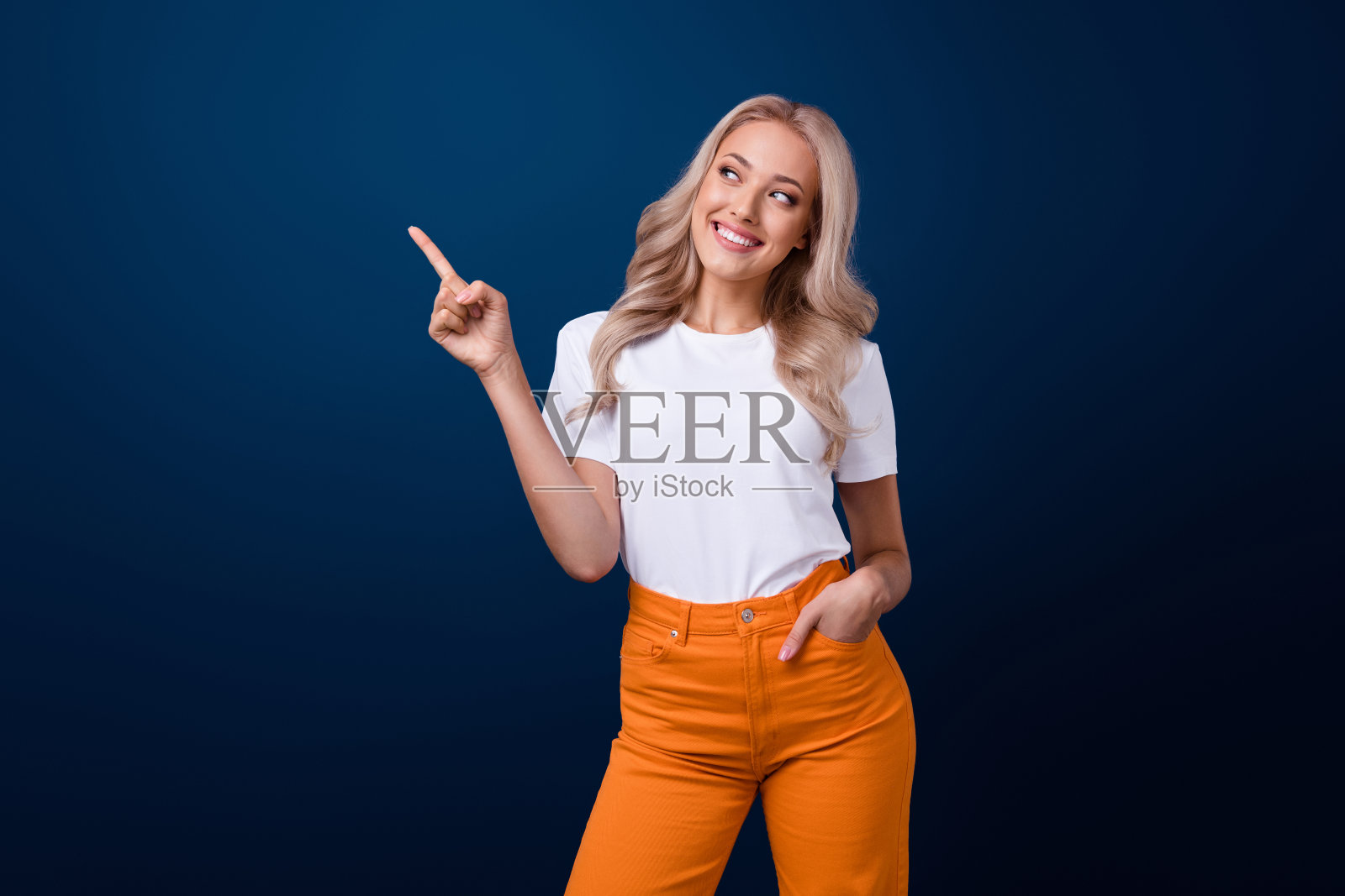 迷人可爱的女孩穿着时髦的白色衣服，在深蓝色的背景上展示新奇的横幅空白空间照片摄影图片