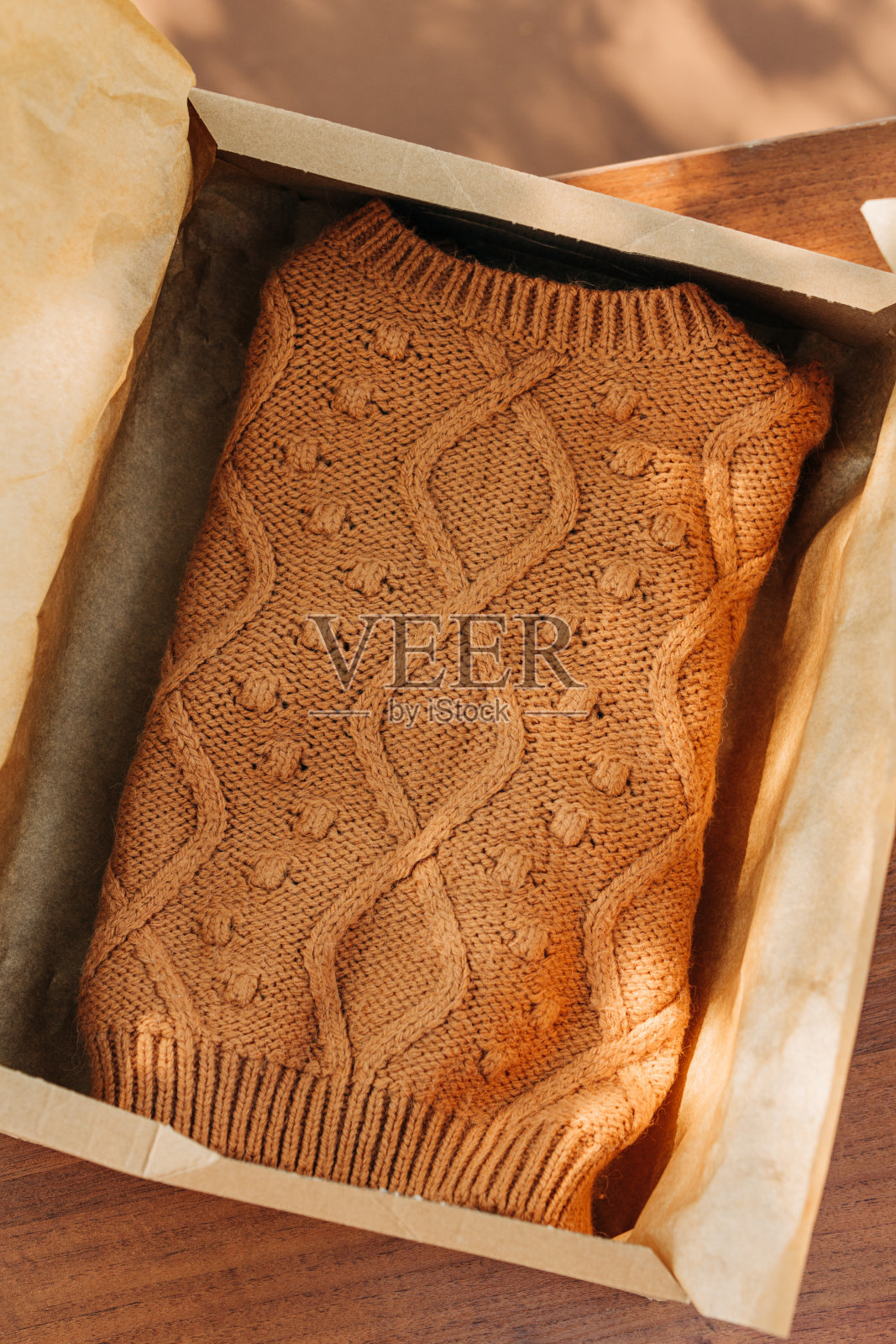 放在户外桌子上的纸盒里的复古毛衣。照片摄影图片