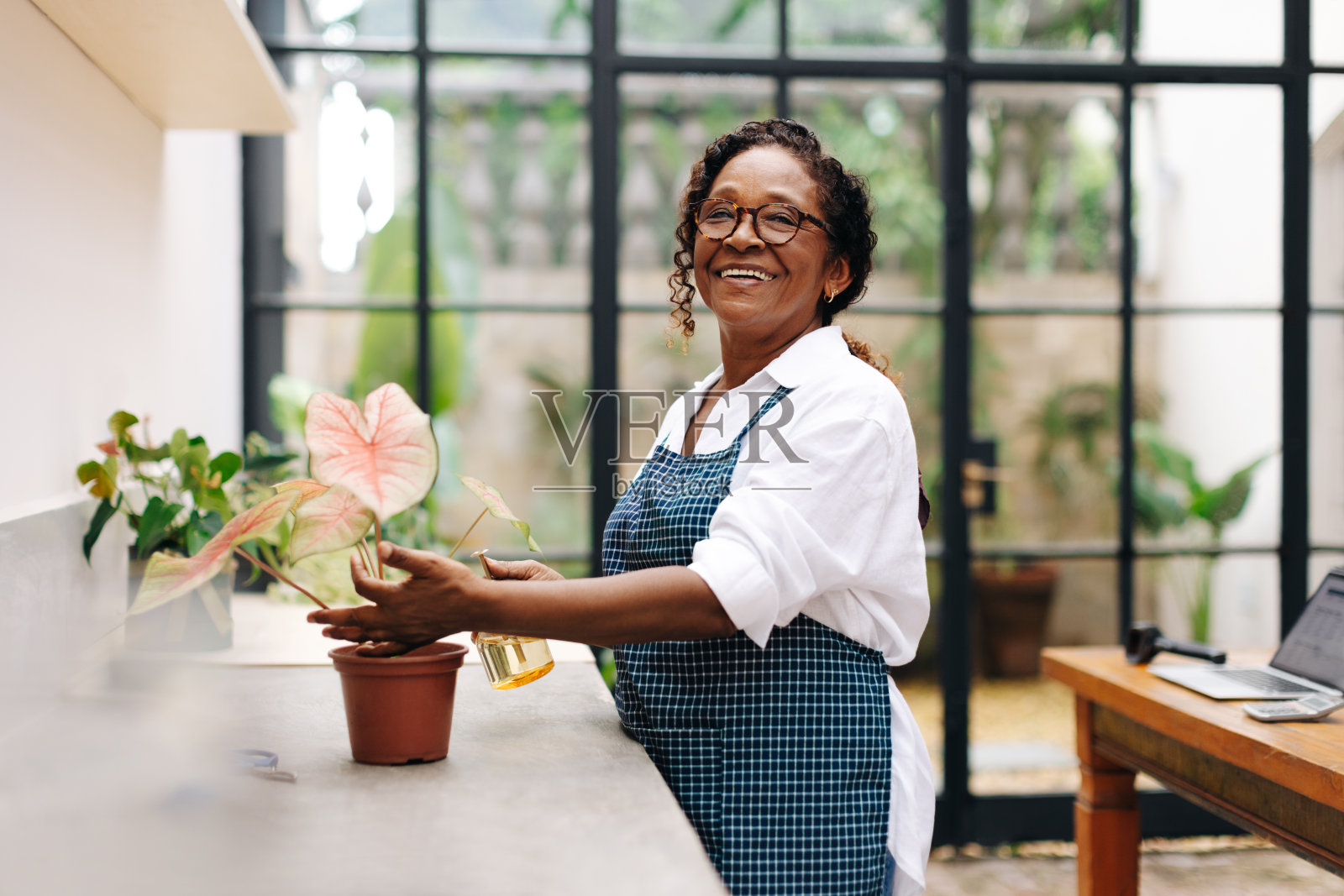 快乐的插花师在她的店里照料一株植物照片摄影图片