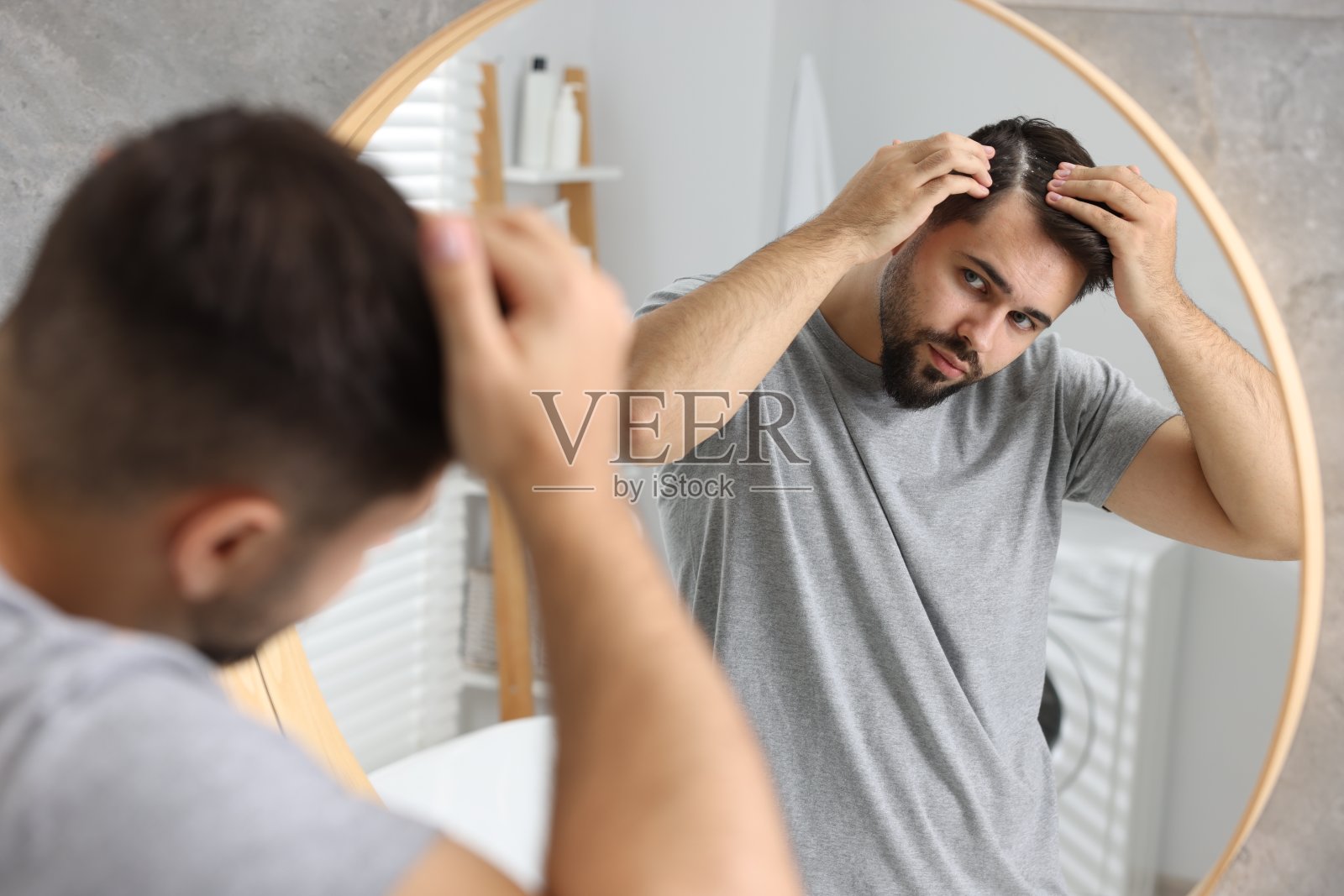 在浴室的镜子前，一个黑发上有头皮屑的男人照片摄影图片