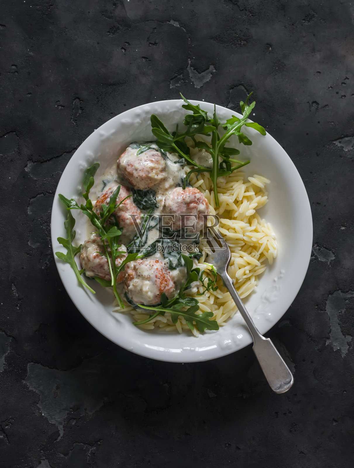 奶油酱三文鱼肉丸意大利面，菠菜和芝麻菜——在黑暗背景下的美味午餐，俯视图照片摄影图片