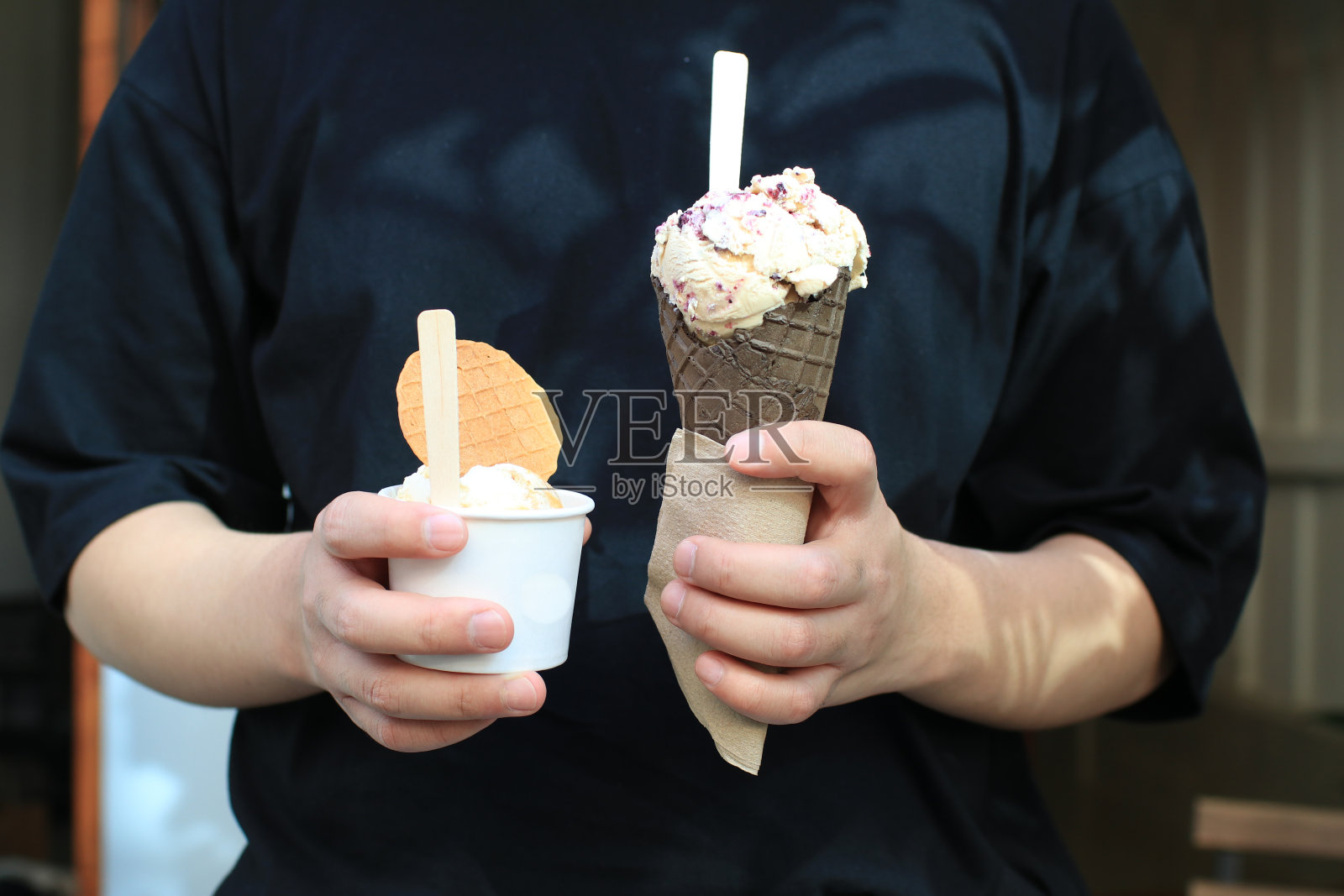 一个人在吃华夫蛋筒里的甜冰淇淋。享用冰淇淋的甜点。手里拿着美味的食物照片摄影图片