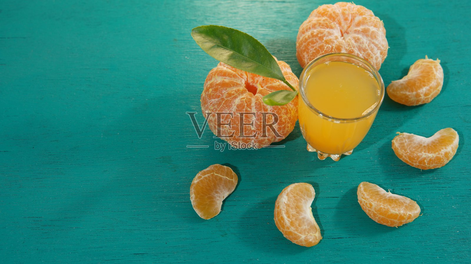 一杯橙汁和在绿松石背景上剥皮的橙子。健康生活主题，健康饮食主题。健康新鲜的橙汁，健康的生活方式照片摄影图片