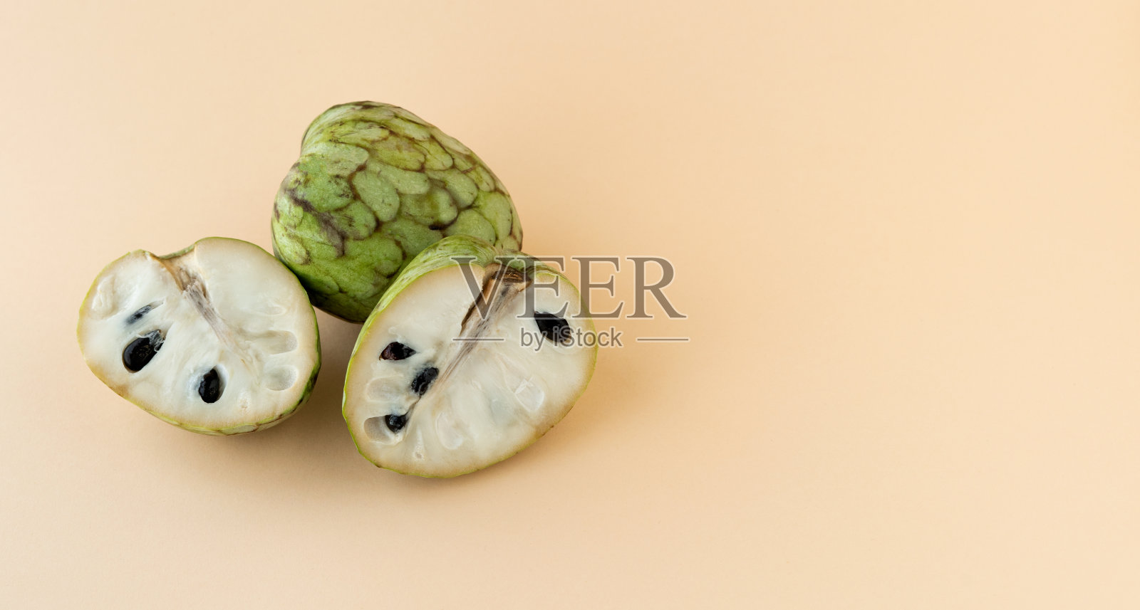 番荔枝。奶油色背景上的整个蛋奶冻苹果和半个蛋奶冻苹果。副本的空间。照片摄影图片