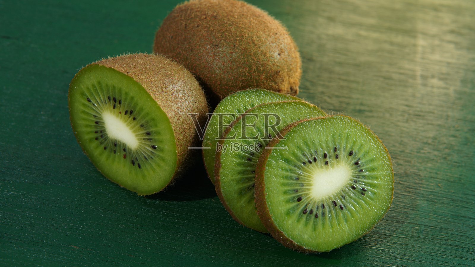 绿色木板上的猕猴桃。整个猕猴桃和切片猕猴桃。健康食品主题，健康生活方式主题，饮食主题，健康水果主题照片摄影图片