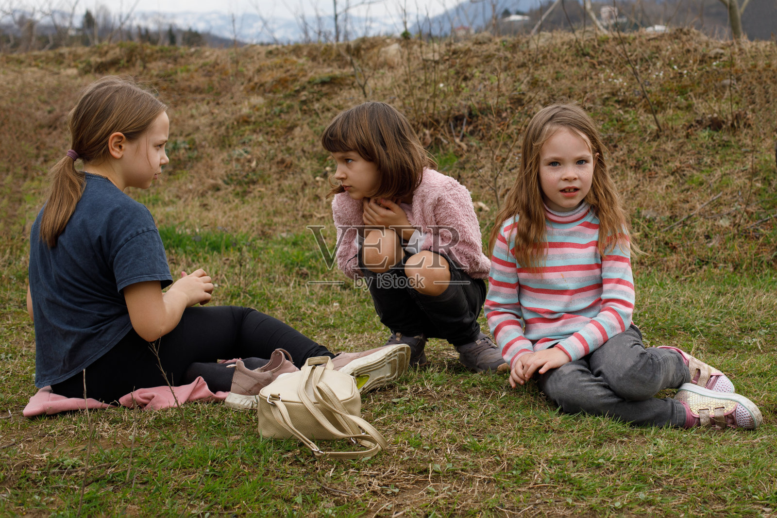 孩子们坐在乡下的草地上照片摄影图片