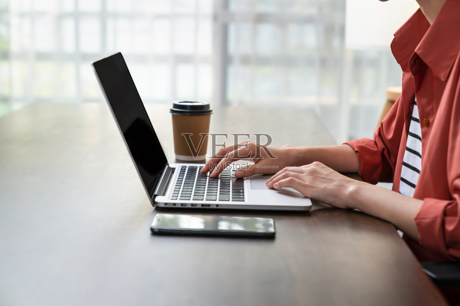 女性在办公室的桌子上使用数字笔记本电脑和智能手机。照片摄影图片