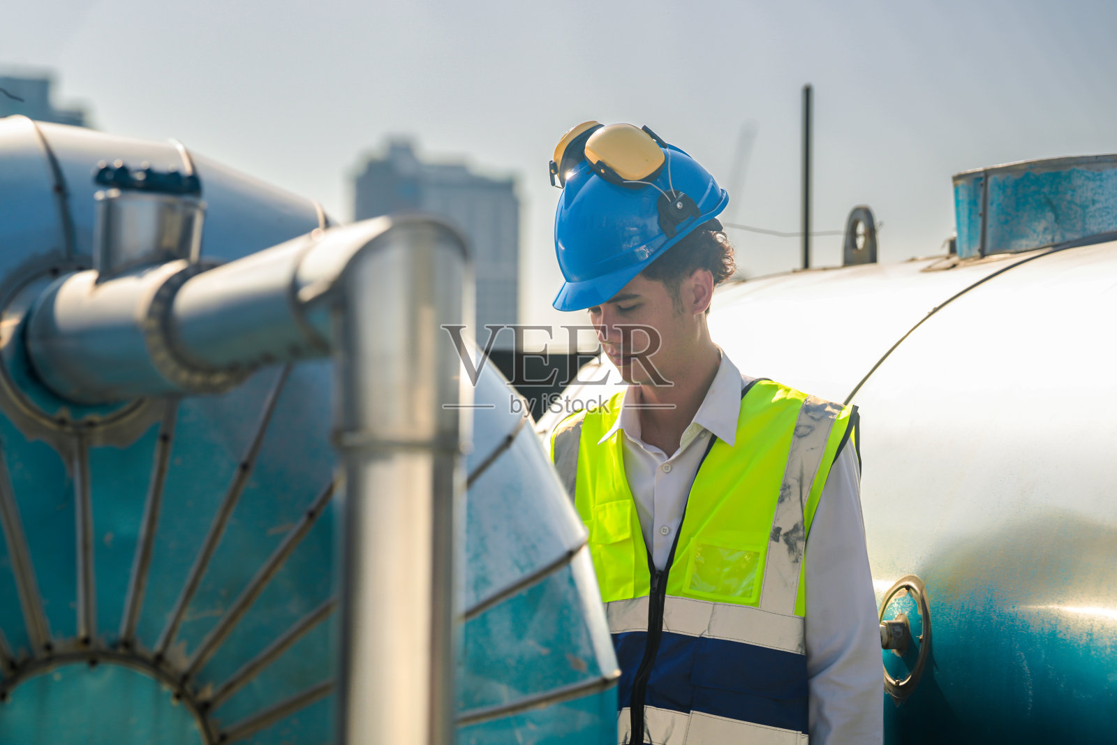 集中技术人员对屋顶供水系统、远处高层建筑进行维护检查。照片摄影图片