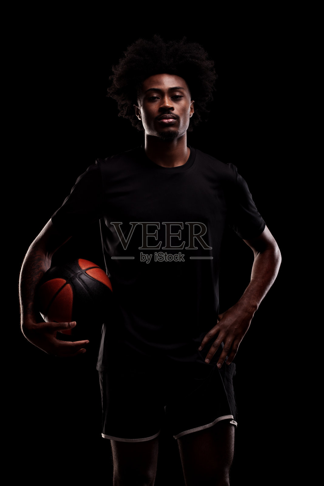 拿着球的篮球运动员。黑人背景下的年轻非裔美国运动员。照片摄影图片