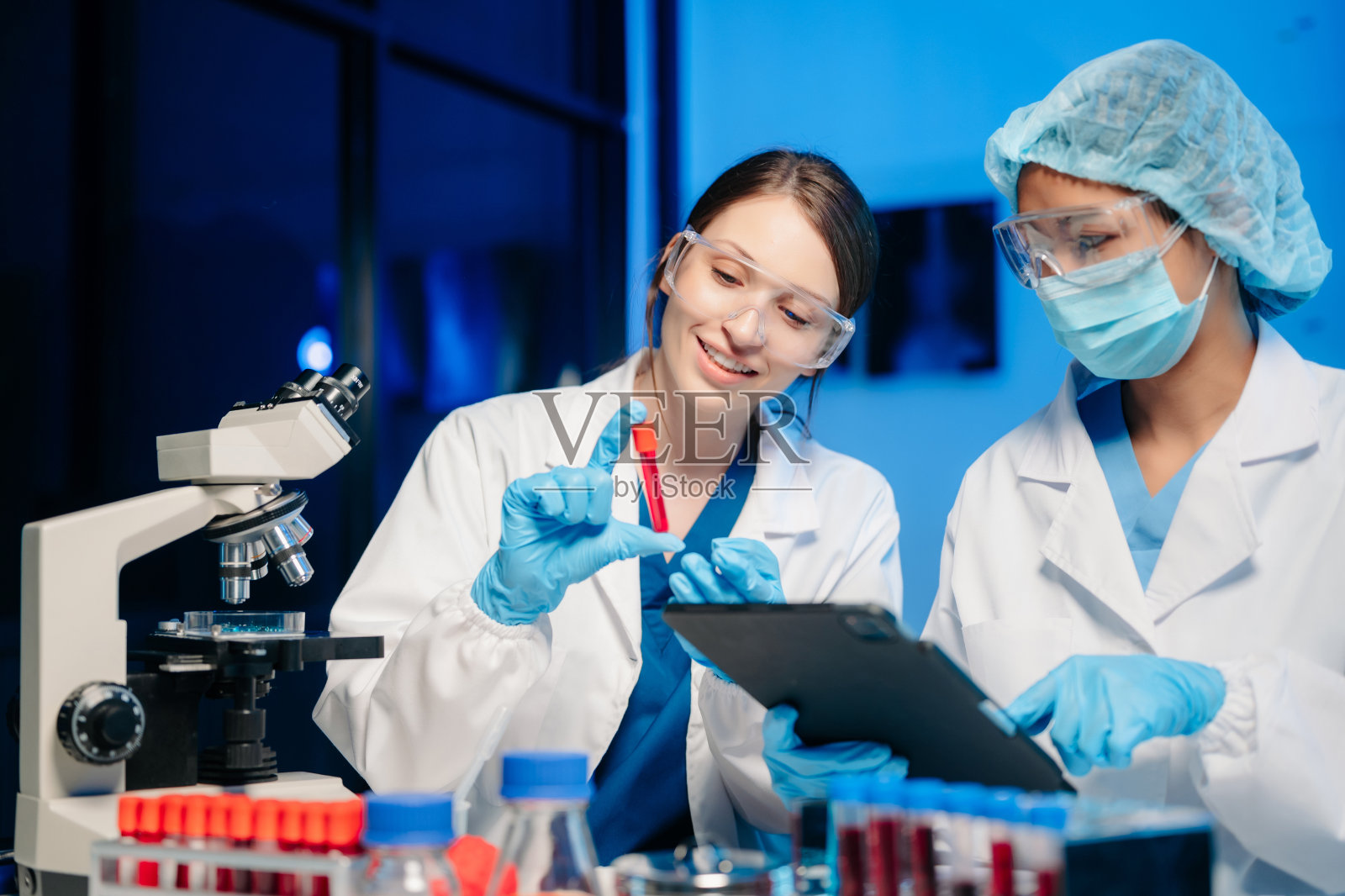 现代医学研究实验室两位科学家工作肖像，使用数码平板，分析样本，谈话。照片摄影图片