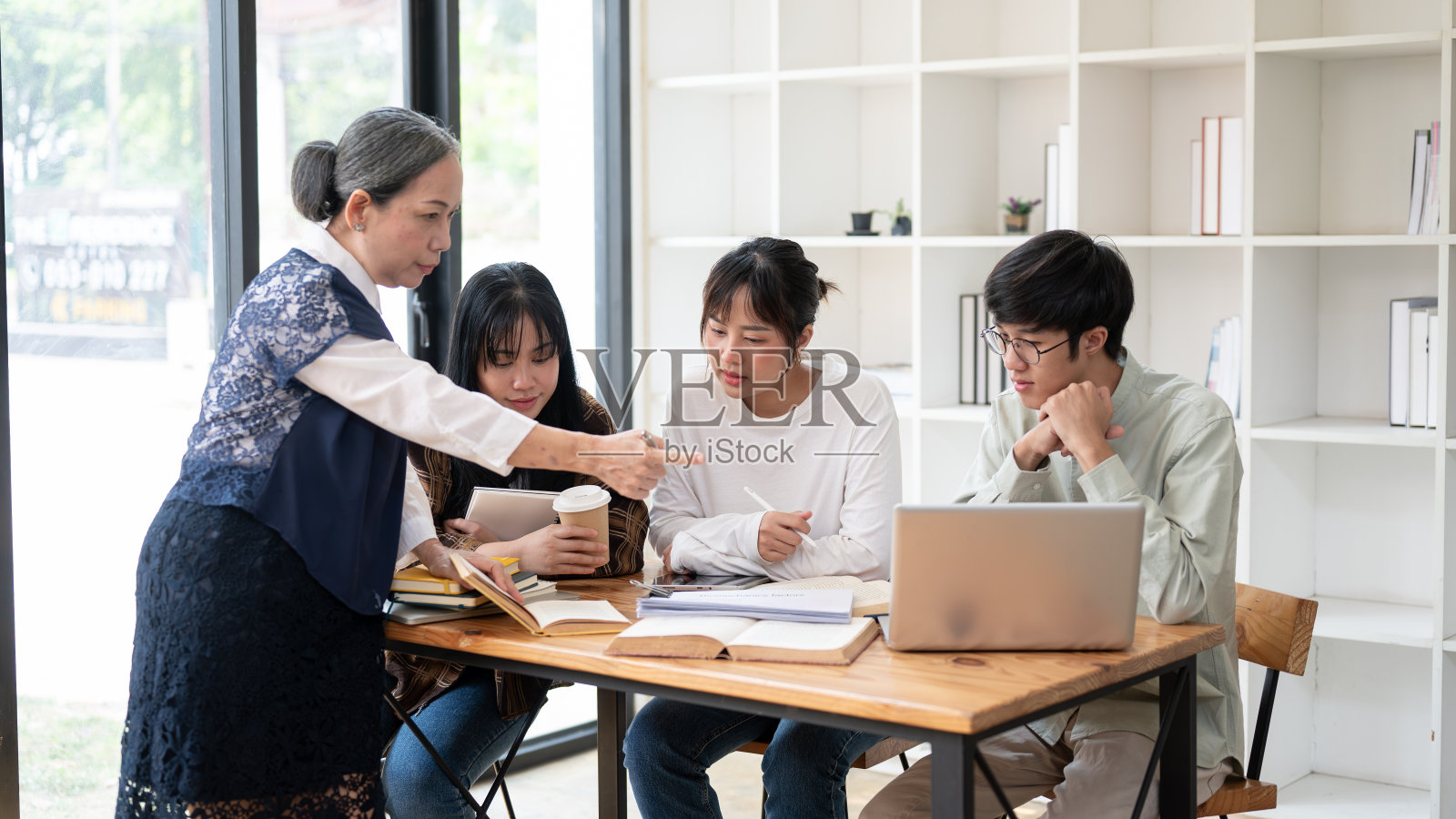 一位成熟的亚洲女教师教授正在教室里给她的学生讲课。照片摄影图片