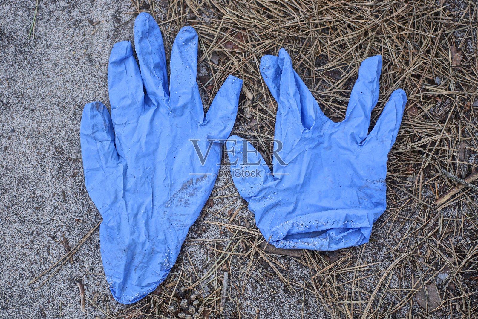 灰色的地上放着两只又旧又脏的蓝色医用橡胶手套照片摄影图片