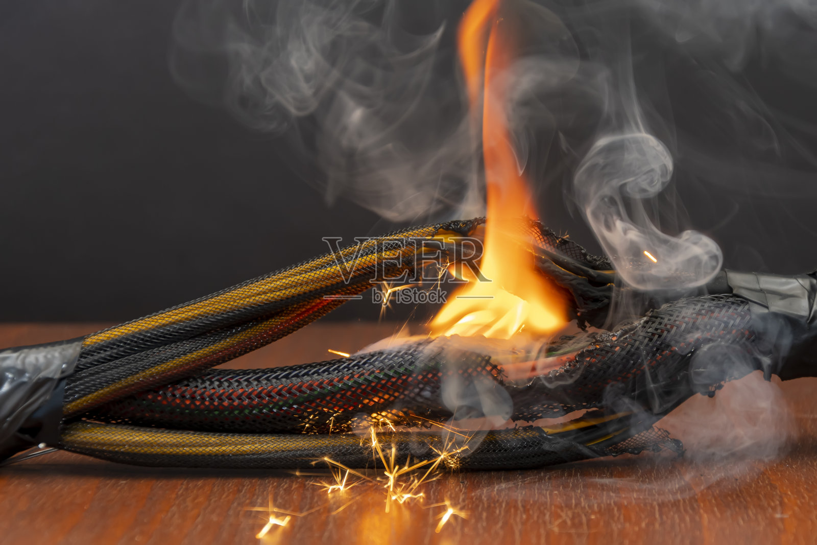 电线和电线被照亮在黑暗的背景上。计算机上的绞合线短路。火焰、火花和烟雾。照片摄影图片