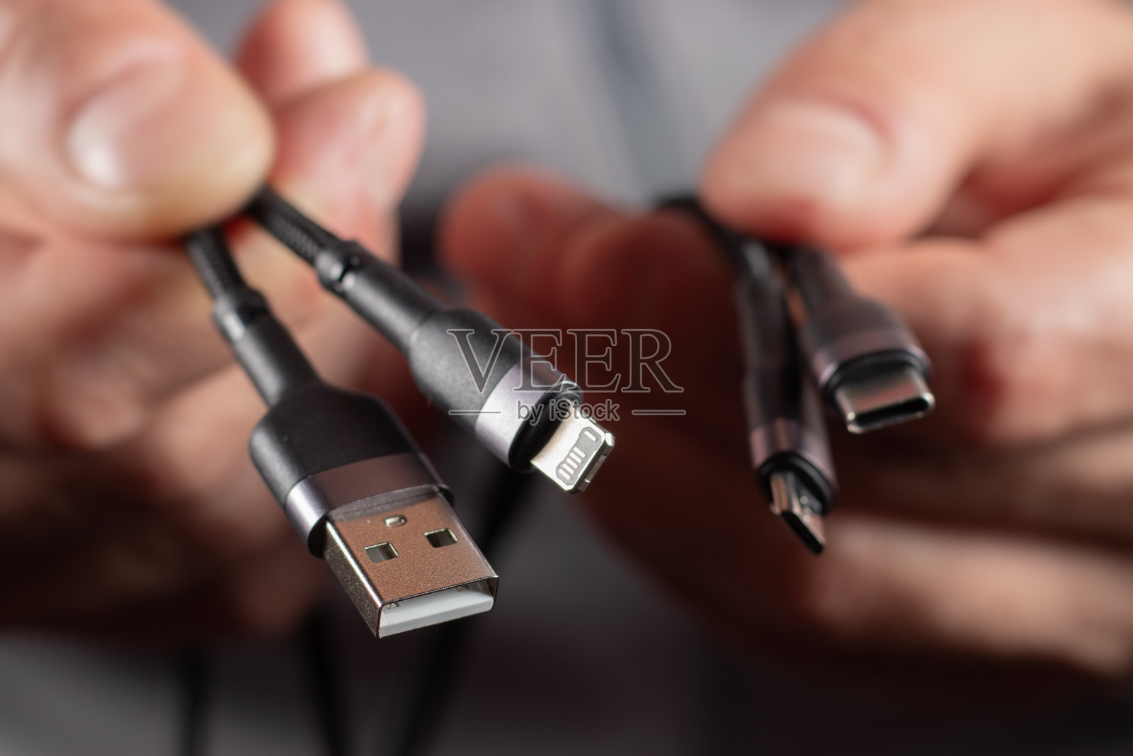 这只手握着一根通用USB电缆。USB Type C, Micro USB, USB lightning照片摄影图片