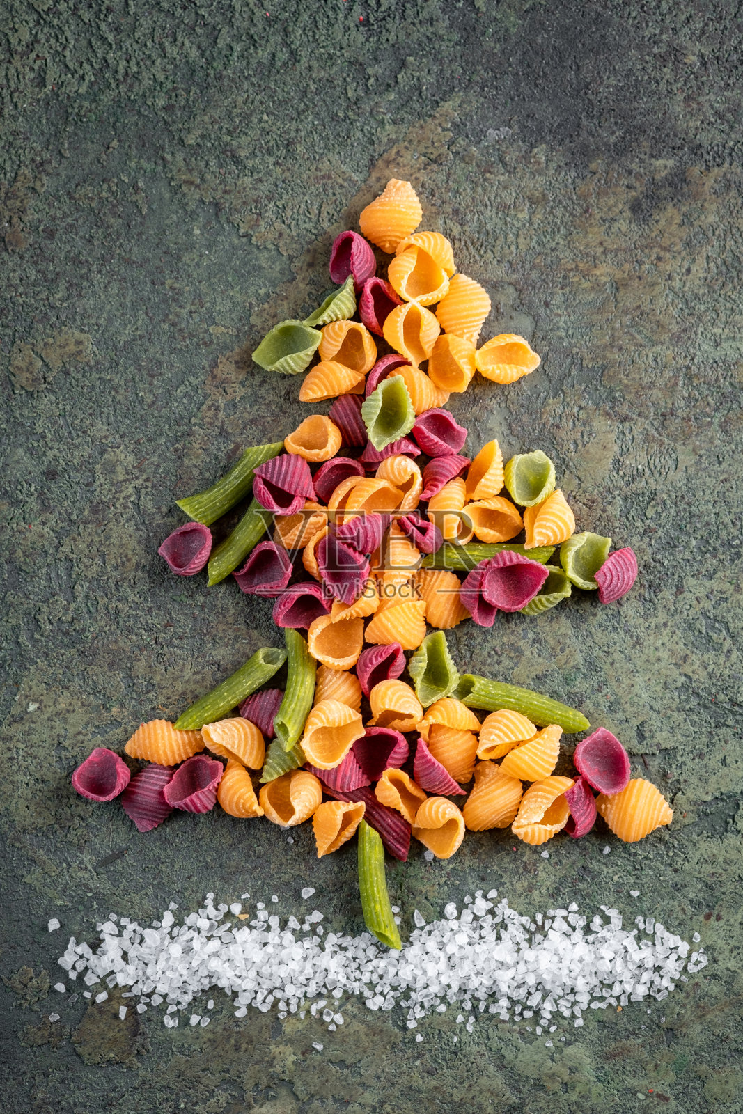 在石头背景上用生的彩色面食做成的圣诞树。圣诞节的概念。照片摄影图片