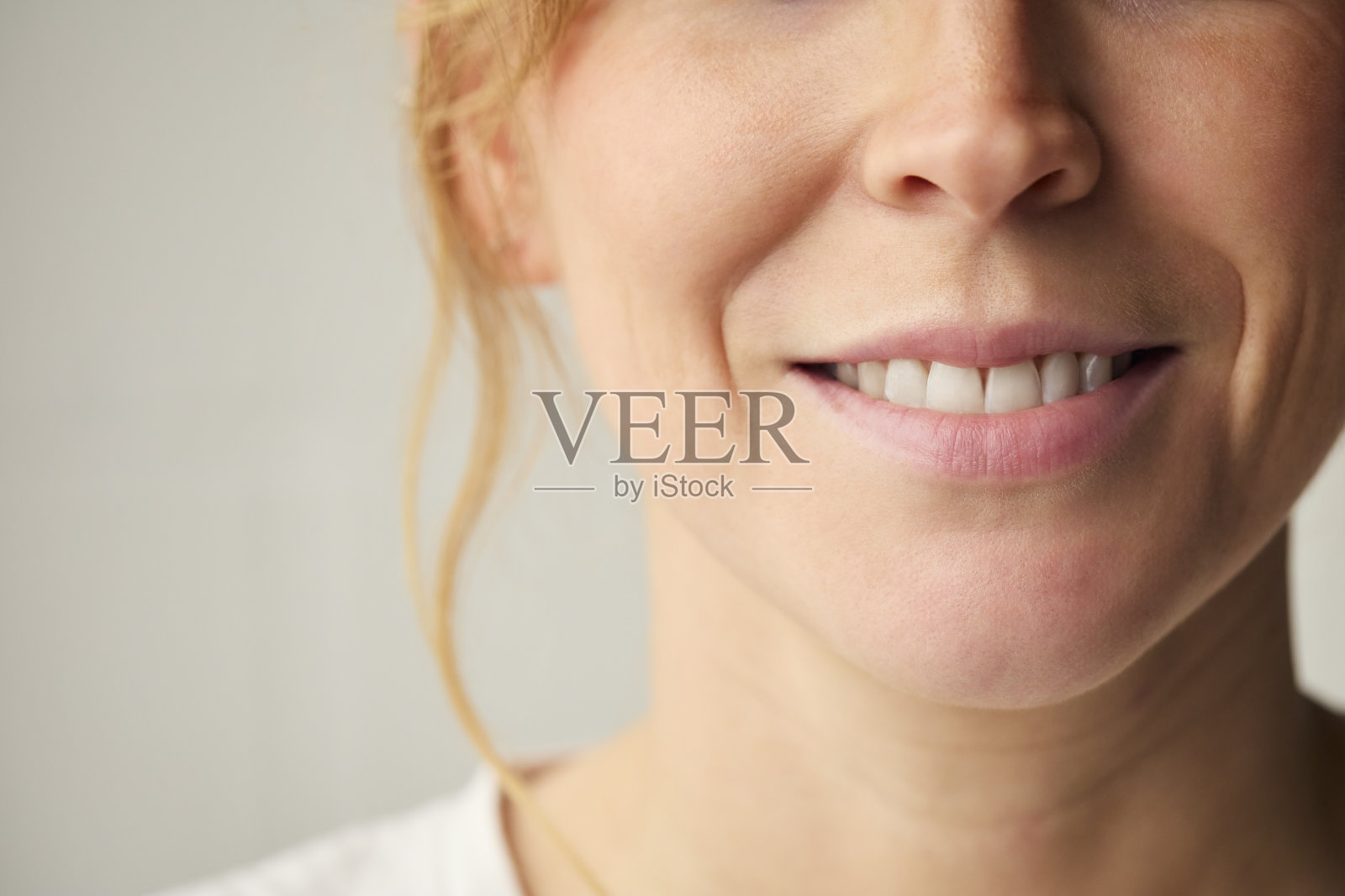 工作室拍摄的女人微笑对平原的背景与嘴唇和牙齿的特写照片摄影图片